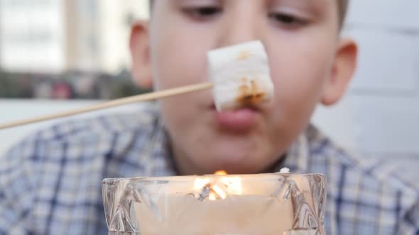 Portrait DOF Caucasian Schoolboy in a Shirt Fries Marshmallows on a Candle Fire Putting on a Wooden