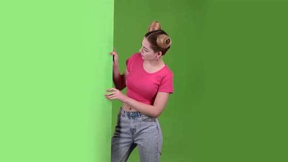 Teen Peeks Out From Behind a Green Board and Shows a Thumbs Down. Green Screen. Slow Motion alt
