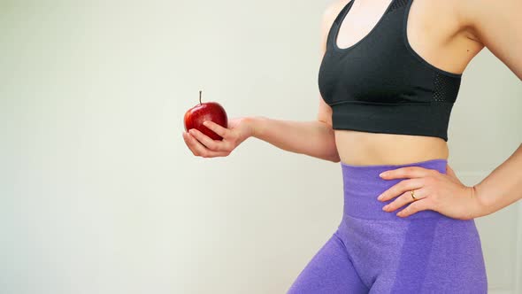 A Slender Athletic Woman's Body Pushes an Apple in Her Hand Slow Motion Closeup
