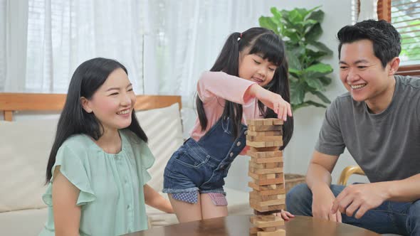 Asian little kid daughter sit on floor enjoy playing toy with family parents in living room at home. alt