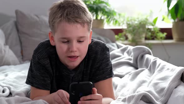Boy Using Smart Phone Looking at Mobile Screen Making Conference Call in App alt
