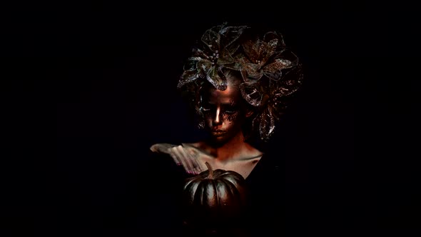 Golden Halloween Woman with Gold Pumpkin. Halloween Fashion Makeup alt