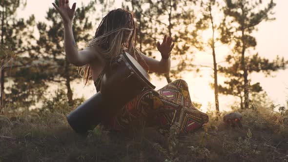 Beautiful Young Hippie Woman with Dreadlocks Playing on Djembe alt