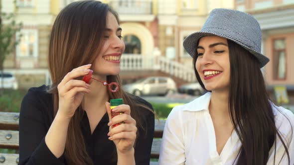 Woman Blows Soap Bubbles on the Bench alt