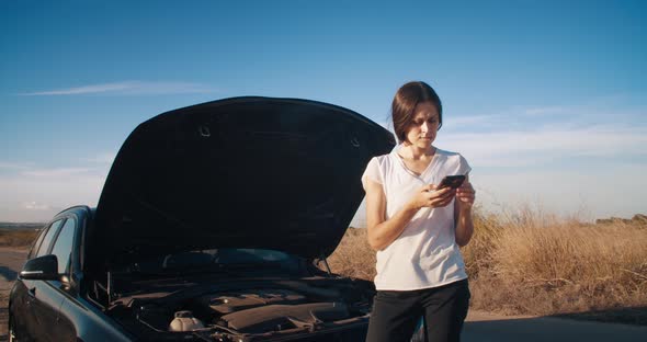 Young Woman in Front of Breakdown Car Using Smartphone Calling Service on Road alt