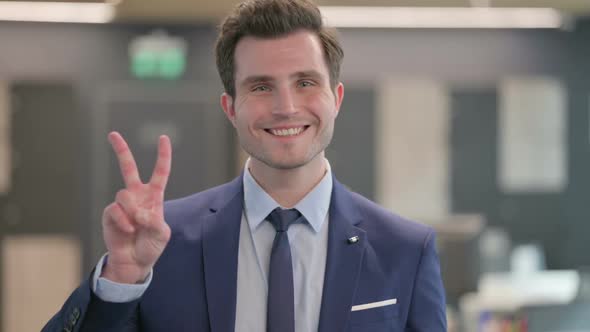 Portrait of Businessman Showing Victory Sign with Finger alt