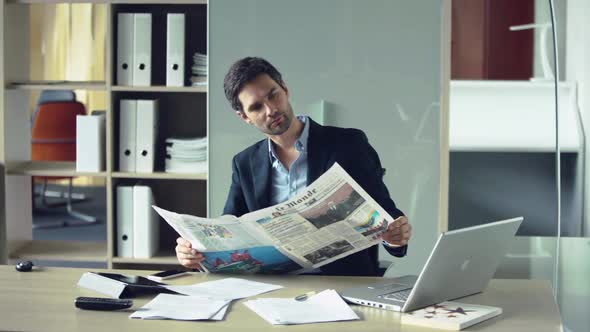 Businessman reading newspaper during break from work alt