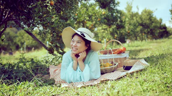 young asian attractive female wearing casual dress sit relax picnic in orange fresh garden alt