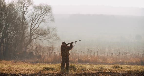 Hunter in Hunting Equipment Saw the Target and Aim with Rifle alt