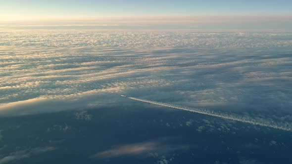 Incredible view from the cockpit of an airplane flying high above the clouds leaving a long white co alt