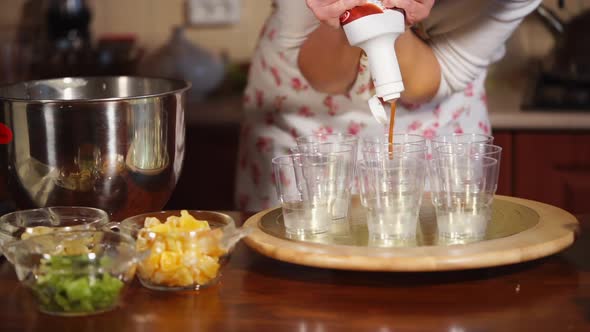 Close Up Shot of the Cups, Where the Cook Pours a Caramel Syrup From the Bottle alt