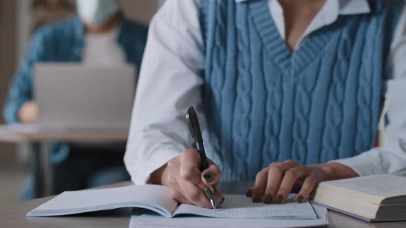 Closeup Unrecognizable Woman Student Sitting at Desk in Classroom Writes in Notebook Noting alt