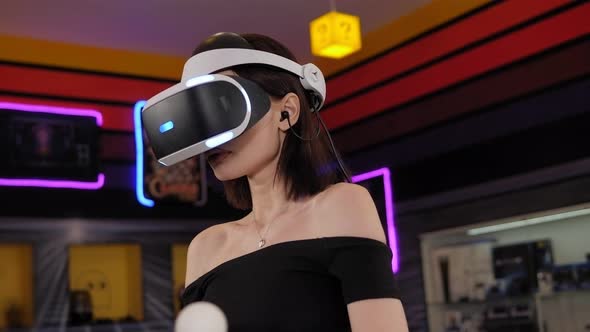 A Young Woman Wearing Virtual Reality Glasses and Hand Motion Controllers alt