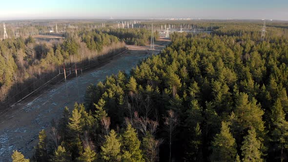 Electric Power Station with Power Lines in a Picturesque Coniferous Forest on a Sunny Winter Day alt
