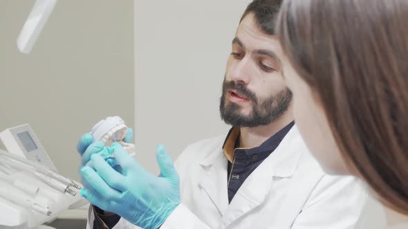 Cropped Shot of a Professional Dentist Showing Teeth Mold to His Patient alt