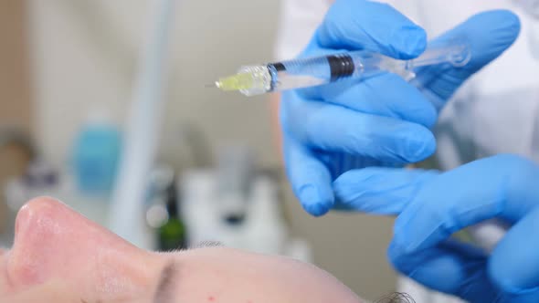 Cosmetologist Makes Skin Beauty Prick for Middleaged Woman with Short Needle alt