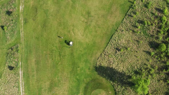 Person and Cart on Green Area Prepared for Playing Golf alt