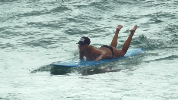 A young woman surfing in a bikini on a longboard surfboard. alt