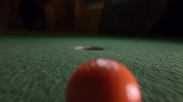 An orange mini golf ball falls into the golf hole and bounces in the pocket on a course. alt