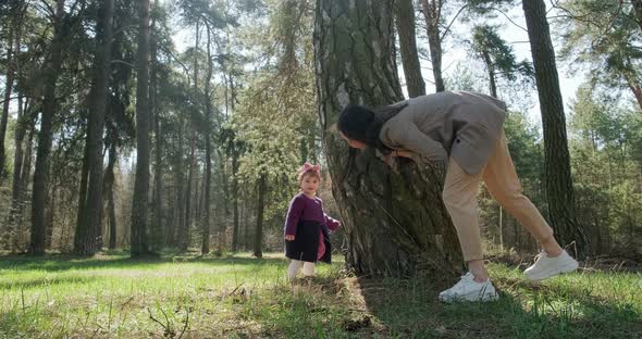 Happy Little Girl Walking and Playing with Mother Among Trees in Coniferous Forest. Healthy Child