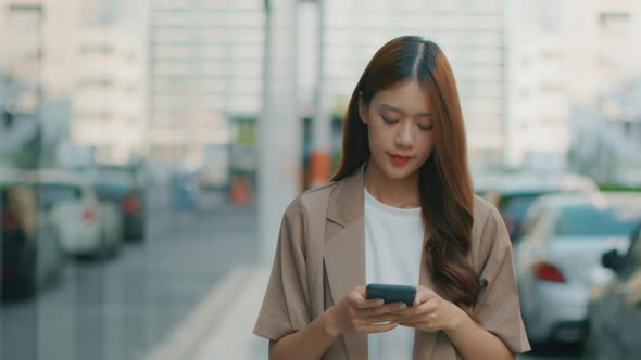 Asian Businesswoman using a mobile phone. Successful Asian Businessperson walking in the street