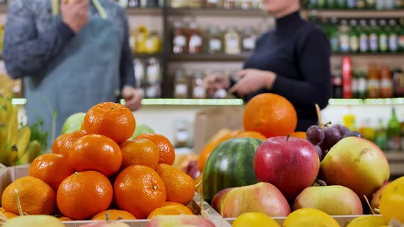 Closeup of Vegetables and Fruits on the Background of the Seller Who Passes the Buyer a Paper Bag