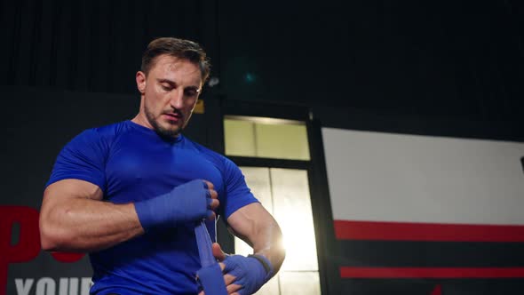 4K Caucasian man wrapping hands with boxing wraps while do boxing exercise at gym. alt