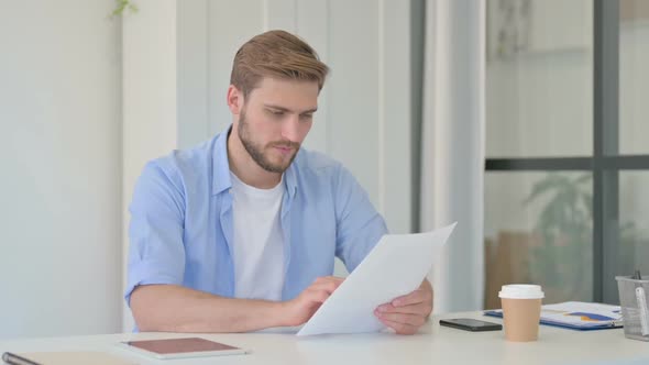 Young Creative Man Celebrating Success While Reading Documents alt