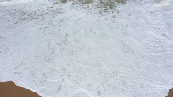 waves and white foam on the sand