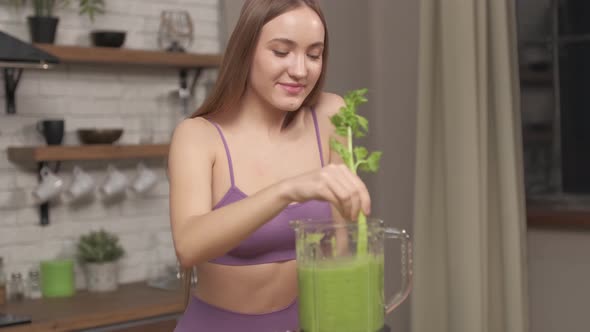 Sporty Woman making, pouring, drinking green vegetable smoothie with blender. alt