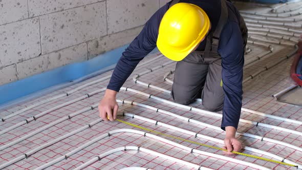 A Professional Worker Arranges Water Heating on the Floor in the House alt