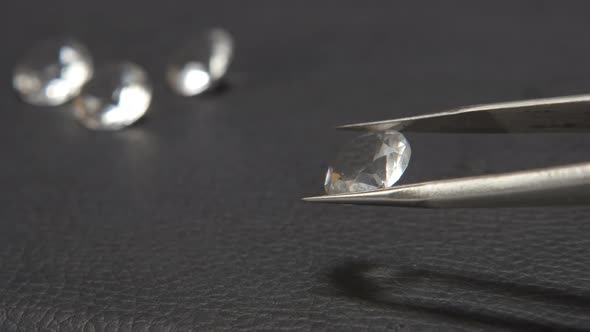 Jeweller takes a diamond in tweezer on black plate