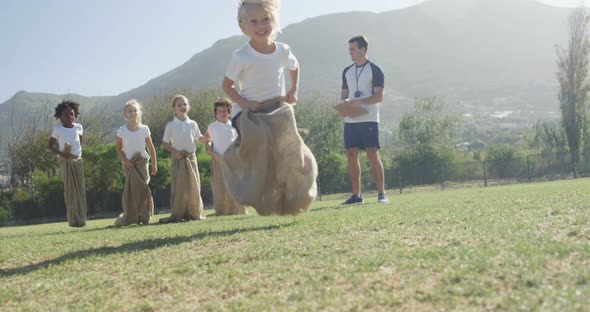 Children playing a sack race in park alt