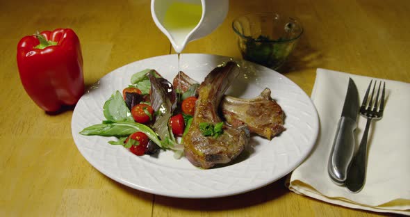 Lamb Chops And Olive Oil Being Poured Over Salad 17b