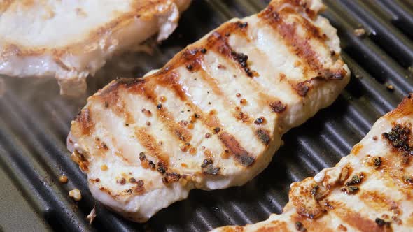 Pork Meat is fried on an electric grill close up.