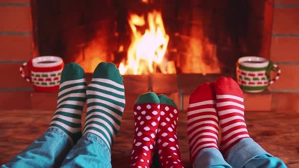 Family In Christmas Socks Near Fireplace. Mother, Father And Child Having Fun