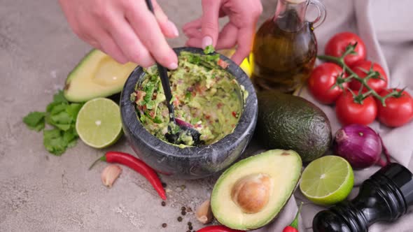 Making Guacamole Sauce  Woman Mixing Chopped Ingredients in Marble Bowl Mortar alt