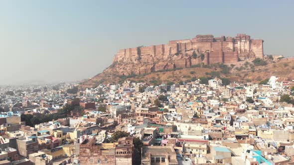 Blue City landscape of Jodhpur surrounding Mehrangarh Fort standing above cliff in Rajasthan, India alt