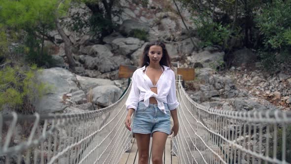 Long Haired Lady in Shorts and White Shirt Walks on Bridge alt