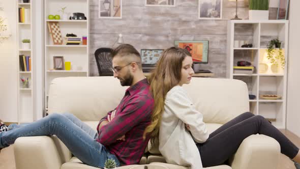 Couple Sitting Back To Back on the Couch with Arms Crossed alt