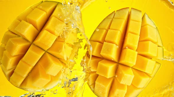 Super Slow Motion Shot of Mango Falling and Splashing Into Water on Yellow Background at 1000Fps alt