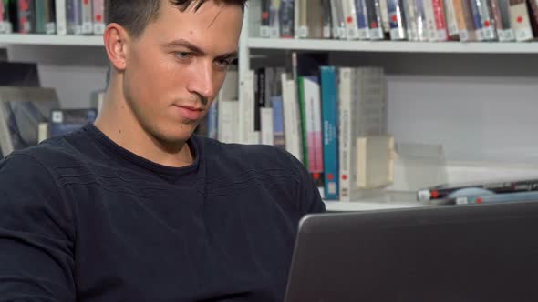 Attractive Male Student Working on Laptop at Campus Library alt