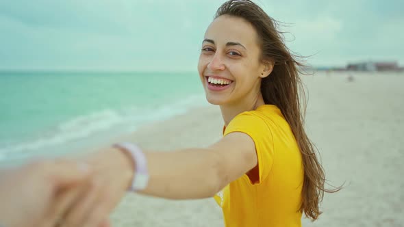 Portrait Happy Woman with Blowing Hair Having Fun on Beach Holding Someone Hand alt