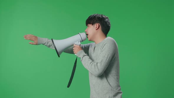 Side View Of Asian Man Speaking On Megaphone In The Green Screen Studio alt