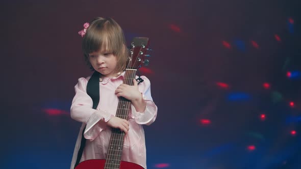 Little Girl in a Pink Vintage Dress Plays an Acoustic Guitar Like a Double Bass