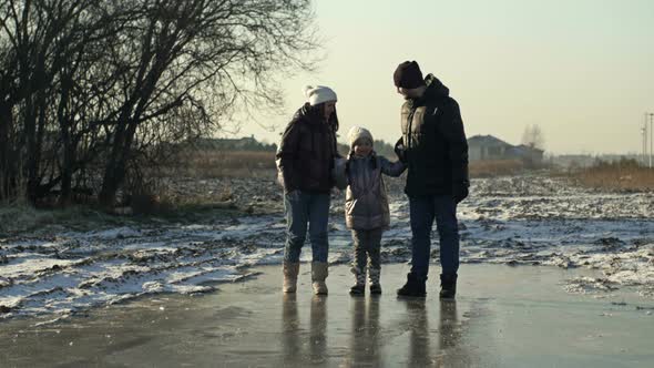 Dad Mom and Daughter 78 Years Old are Walking on the Ice in a Frozen Lake