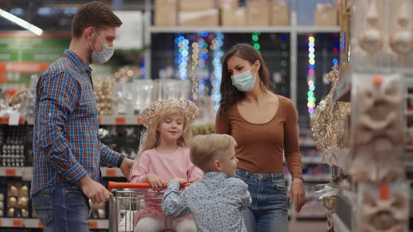 A Married Couple with Two Children in a Shopping Center in Protective Masks in the Coronavirus alt
