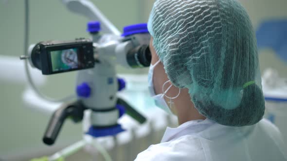 Shooting Over Shoulder of Professional Orthodontist Using Dental Microscope with Camera Showing Oral alt