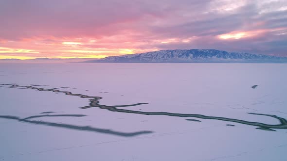 Colorful winter sunset over Utah Lake frozen in winter alt