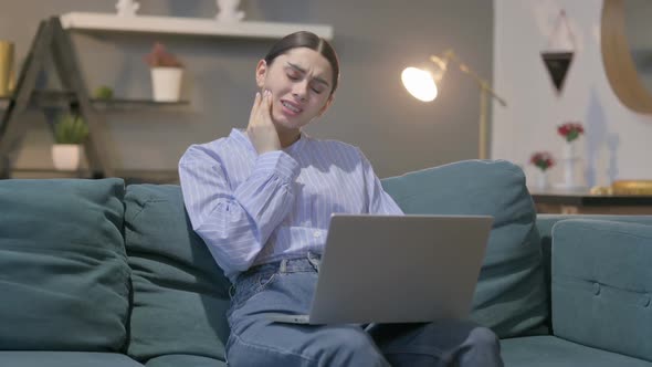 Hispanic Woman with Laptop having Toothache on Sofa alt